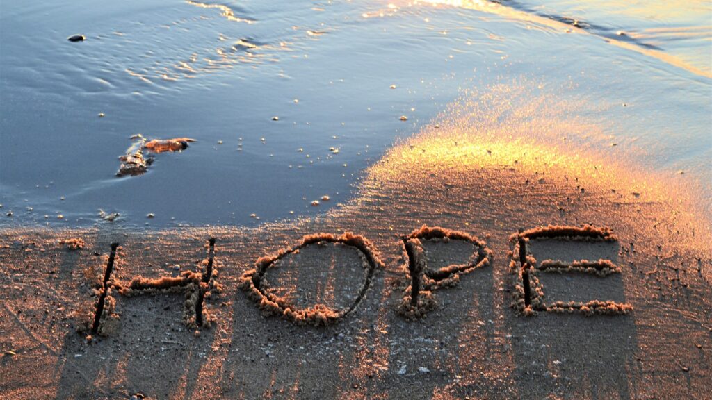 The word hope written in the sand on the beach at sunset